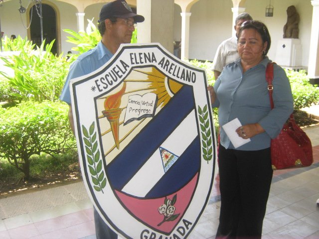Prof. Josefa Hernandez (der.) muestra el escudo nuevo de la Escuela Elena Arellano